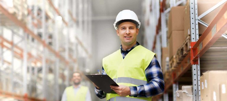 Man wearing hardhat in warehouse with clipboard