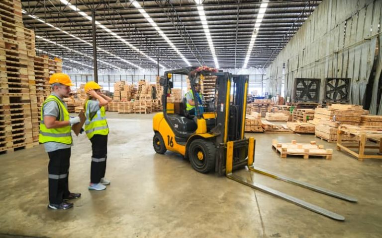 Warehouse workers with forklift and pallets.