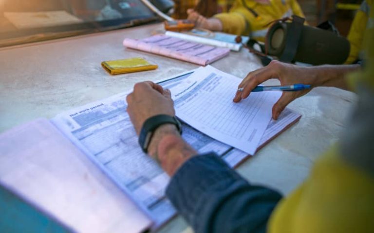 Person filling out paperwork outdoors.