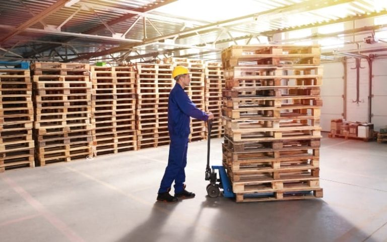 Worker moving pallets in warehouse.