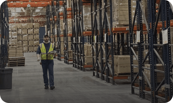 Worker in organized warehouse aisle.