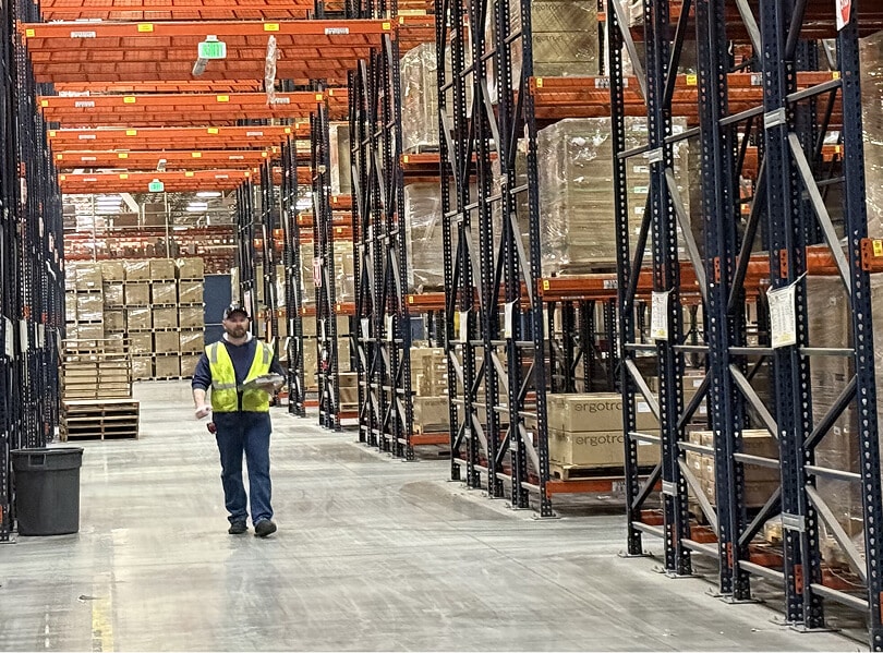 Warehouse worker among stacked pallets.