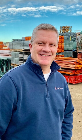 Man in blue sweater at warehouse.