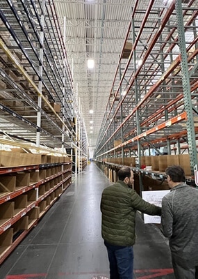 Two men discussing in warehouse aisle