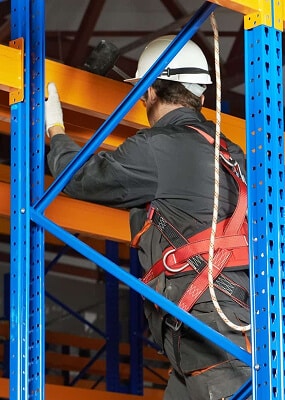 Worker installing shelves with safety gear