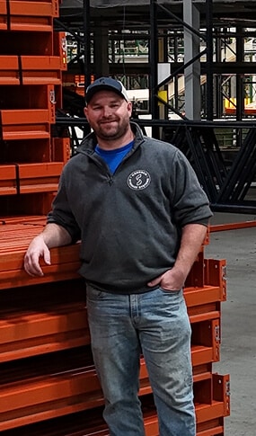 Man standing near orange storage racks.