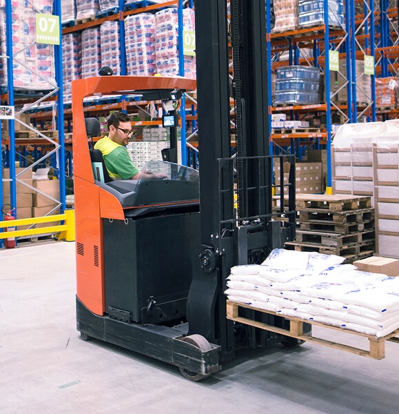Forklift transporting goods in warehouse.