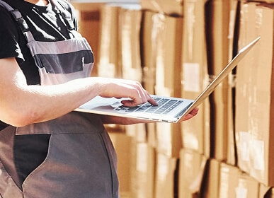 Worker using laptop in warehouse