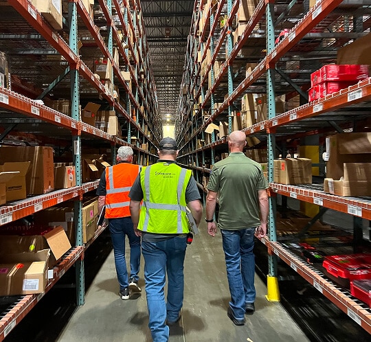 Three workers walking through warehouse aisles