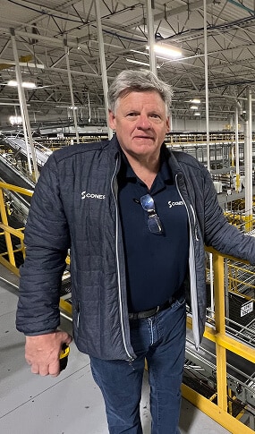 Man in industrial setting, wearing jacket.