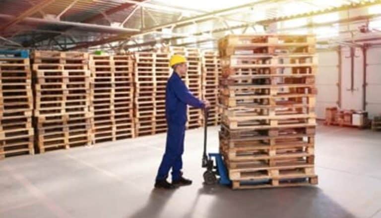 Worker moving pallets in warehouse